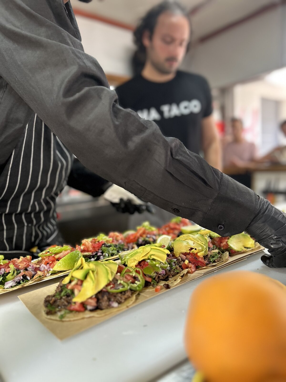 Chef plating a long taco board at an event