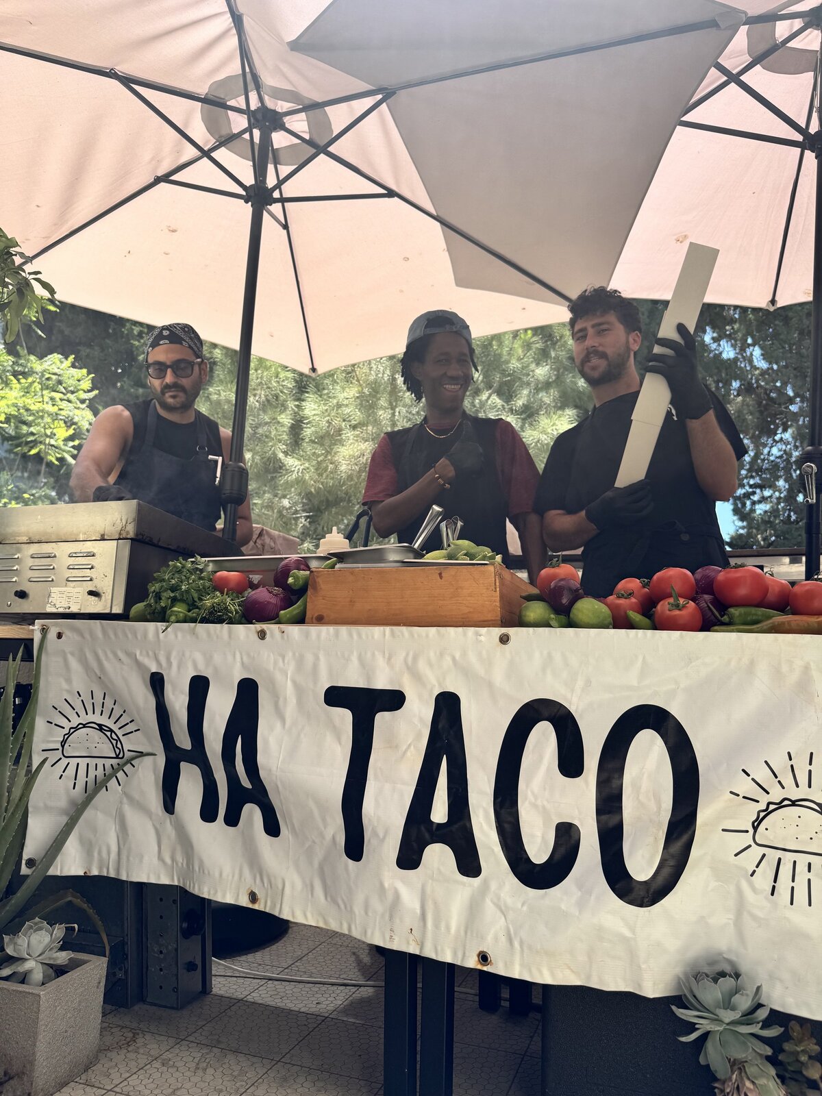 HA TACO team smiling behind the banner in a garden