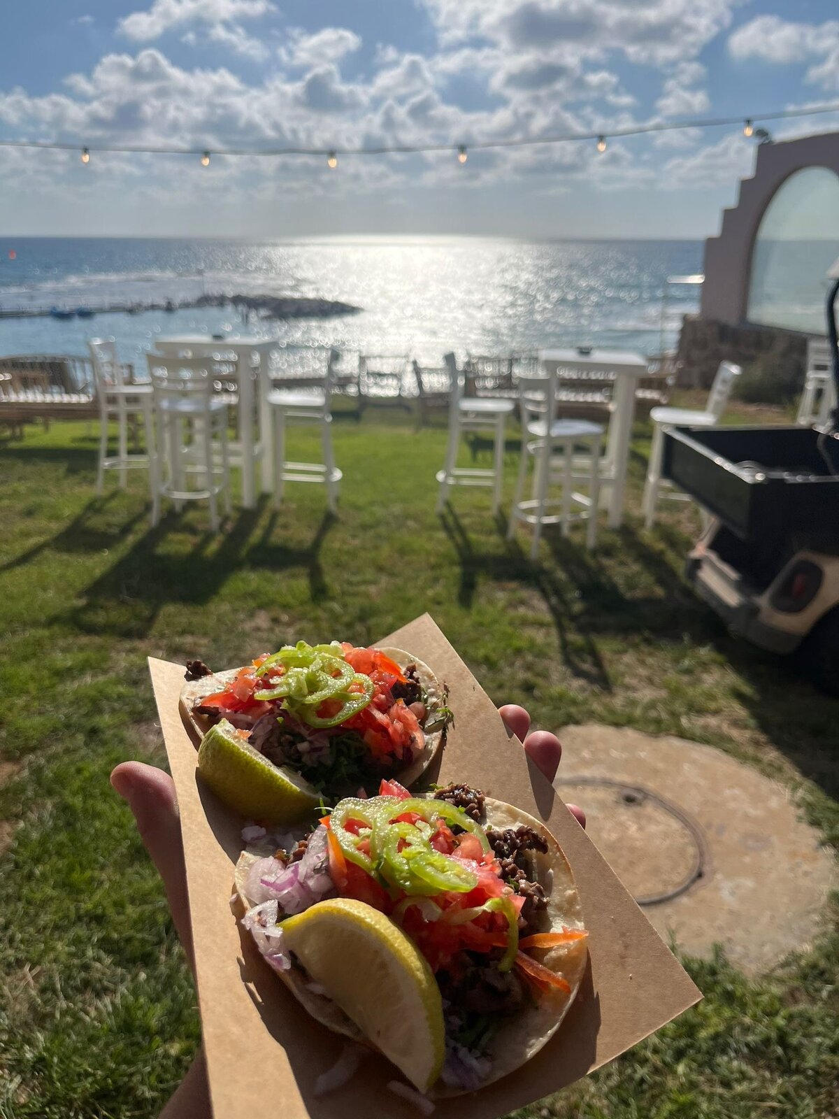 Seaside wedding with white chairs and a taco in hand