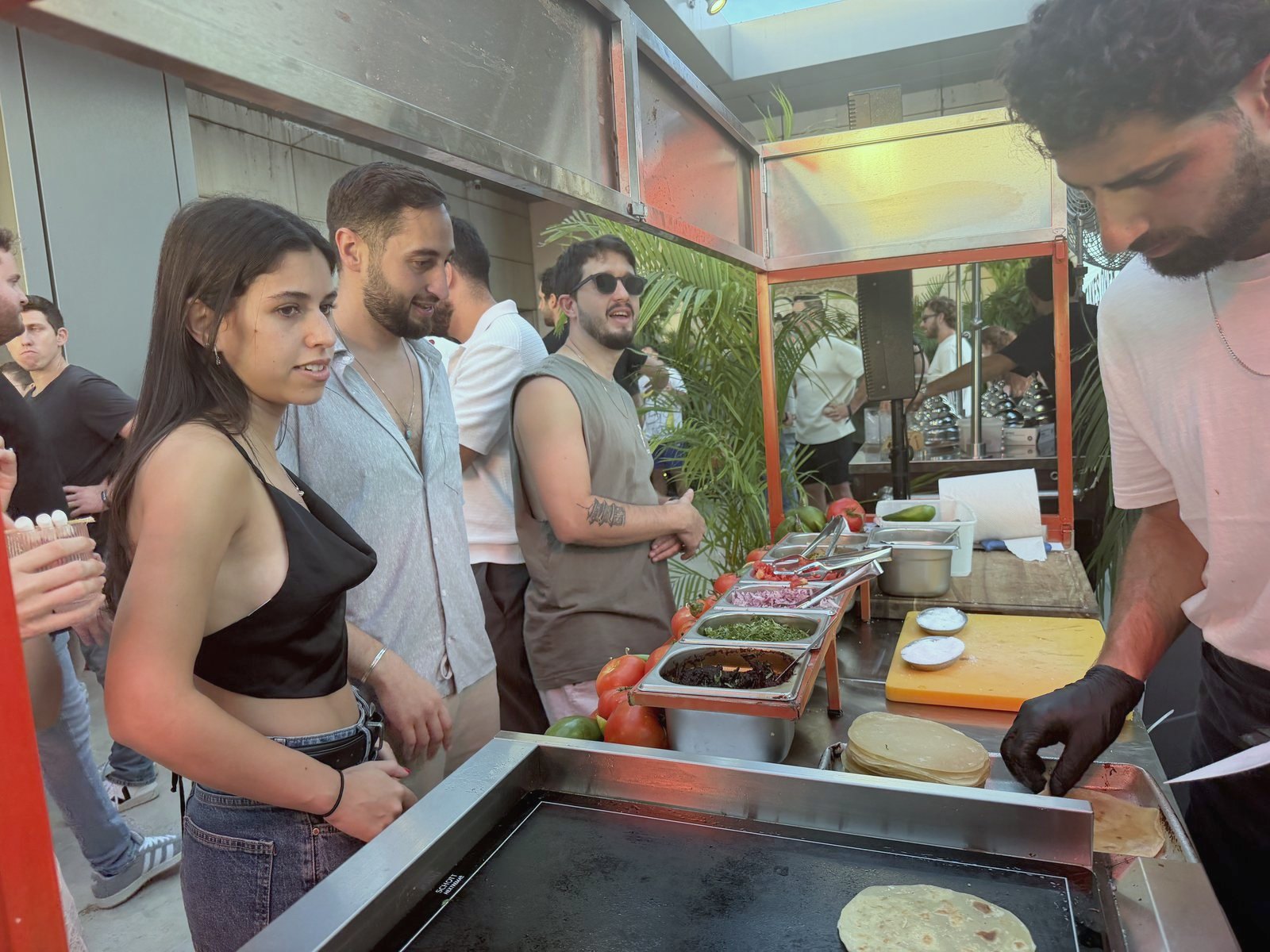 אורחים ליד הפלאנצ׳ה בזמן שהטאקו נבנה