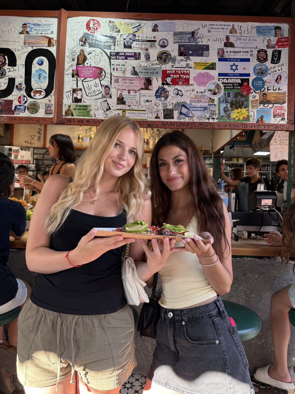Two smiling customers with a taco plate at the stall