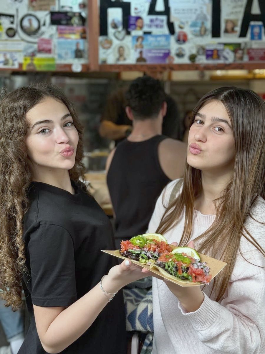שתי חברות עם טאקו ביד מול קיר המדבקות